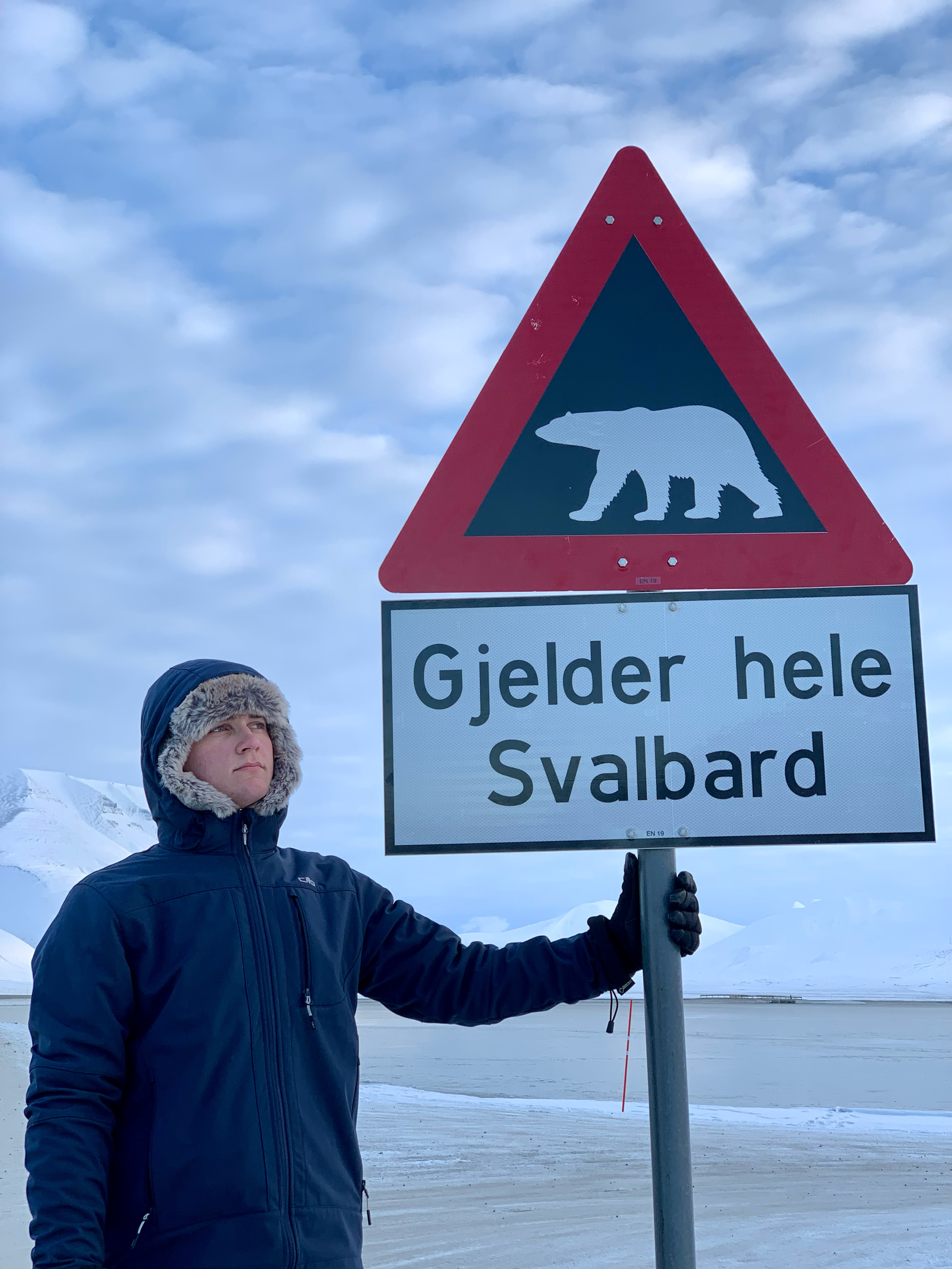 Elev foran advarselsskilt mot isbjørn på Svalbard.