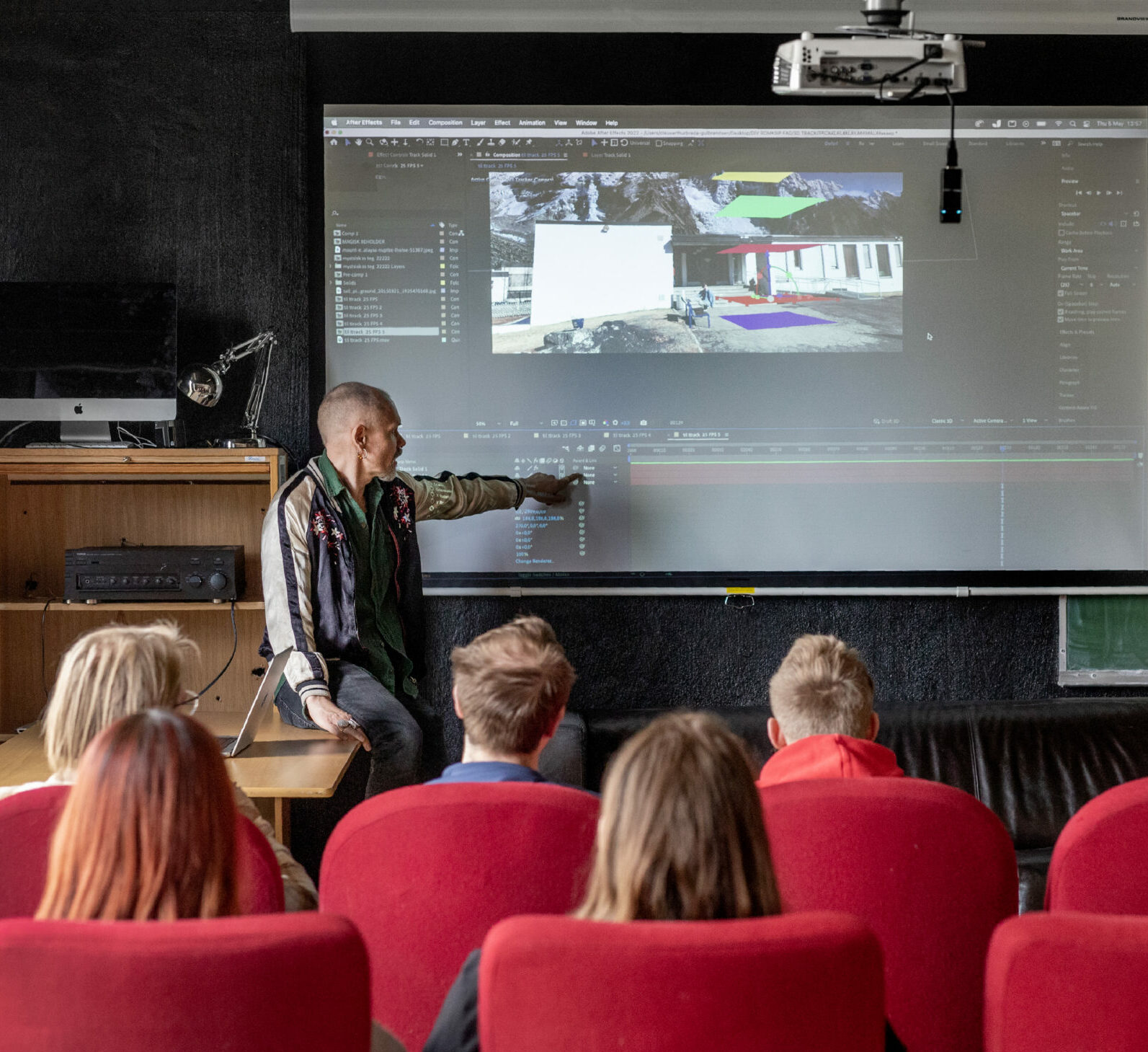 Lærer på Buskerud folkehøgskole viser fram noe på en skjerm foran elever som sitter med ryggen til