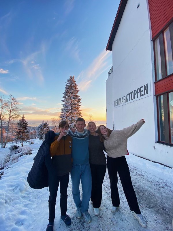 En gjeng ungdommer poserer utenfor Hedmarktoppen i solnedgang. 