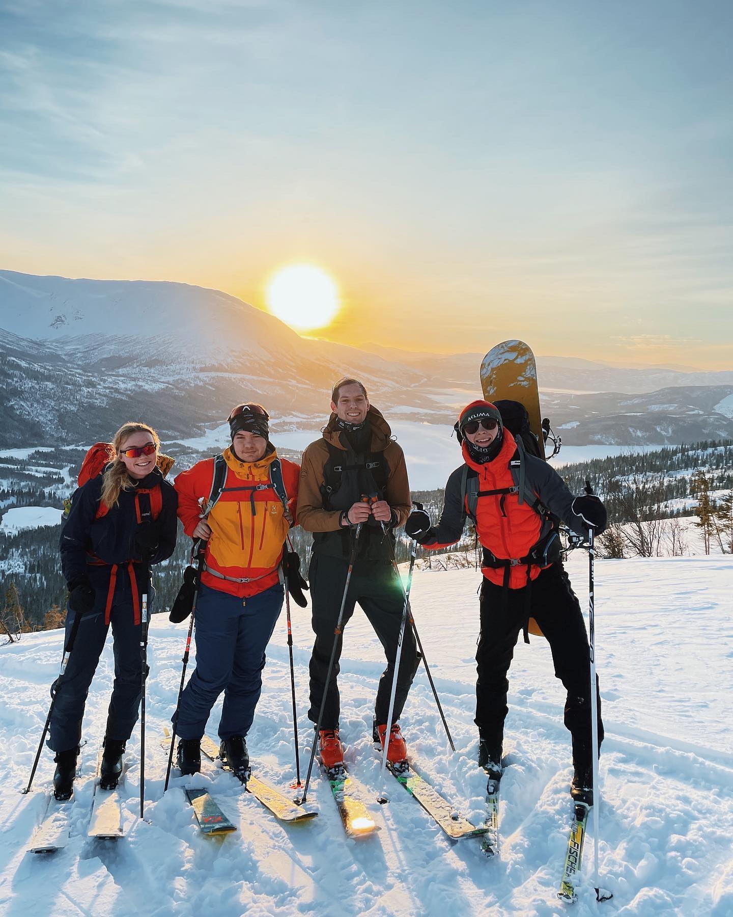 Fire personer har ski på beina og smiler i kamera. 