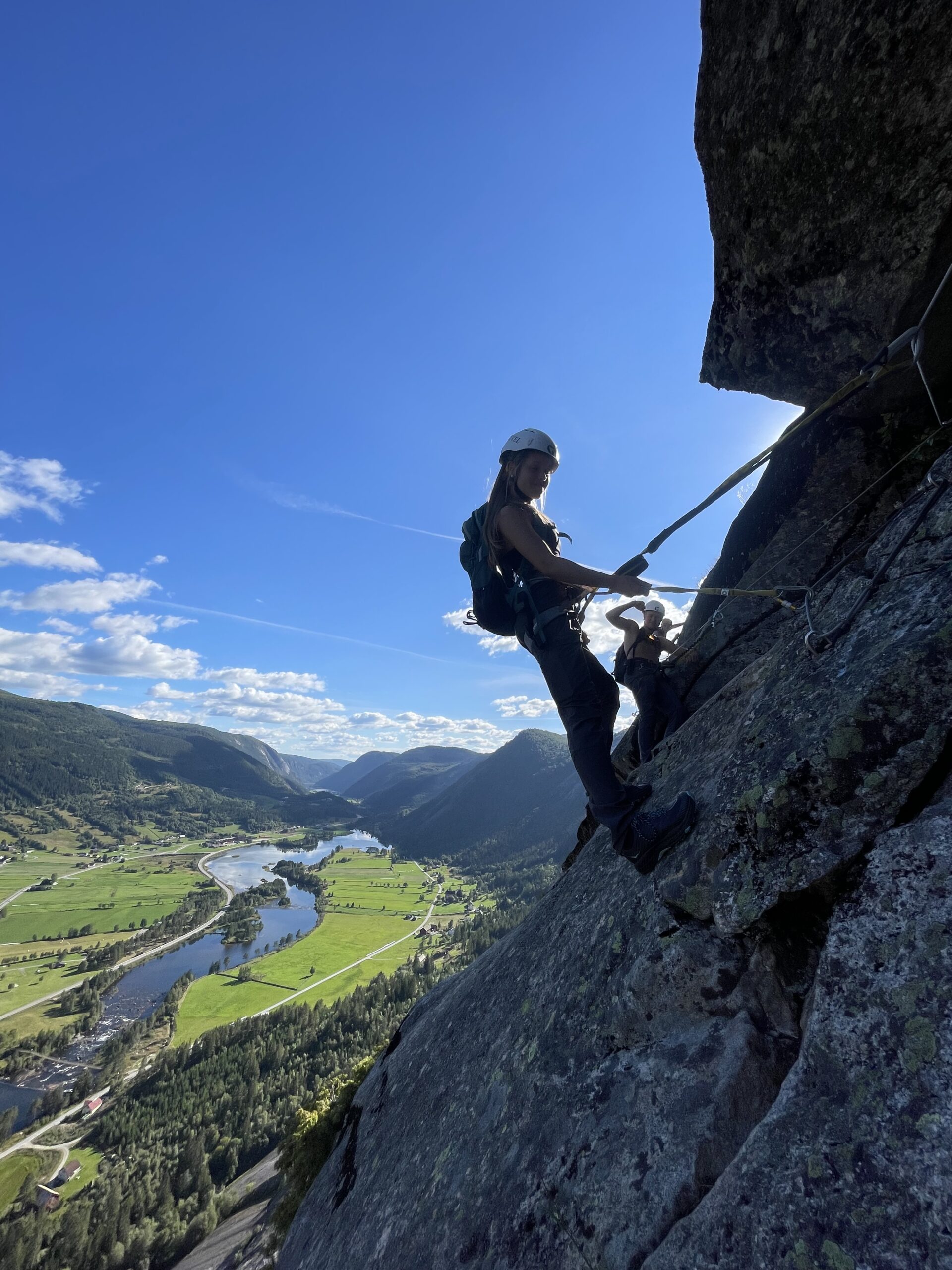 en ung kvinne som klatrer via ferrata i en fjellvegg 