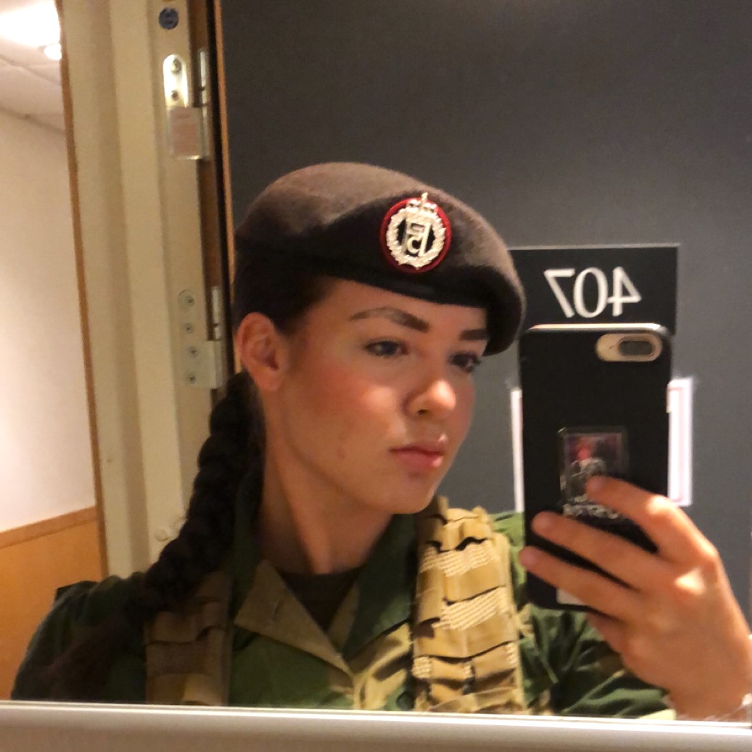 Jente med uniform tar bilde av seg selv i et speil. Folkehøgskole og Forsvaret.