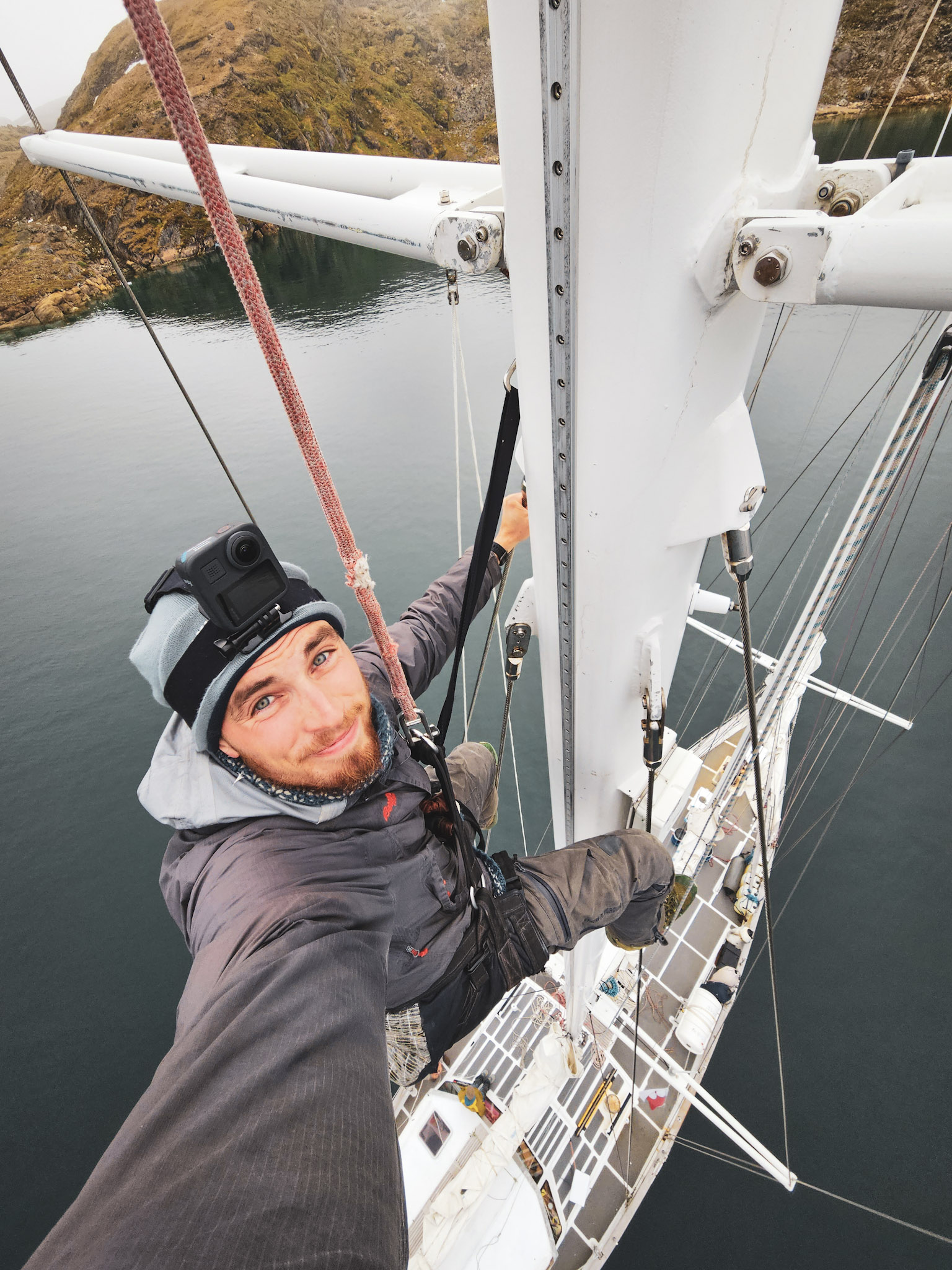 En ung mann tar selfie i toppen av en seilbåt. 